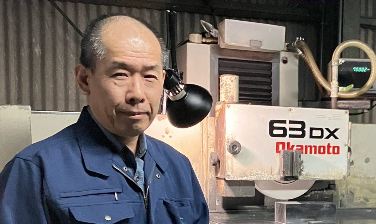 代表 山本 亘（研削盤の前で）